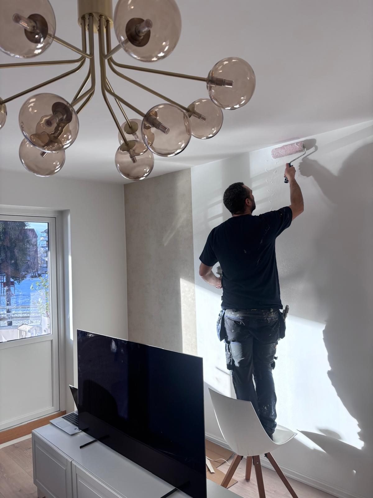 Maler fra Oslo Håndverksmester AS som maler en vegg i en moderne leilighet